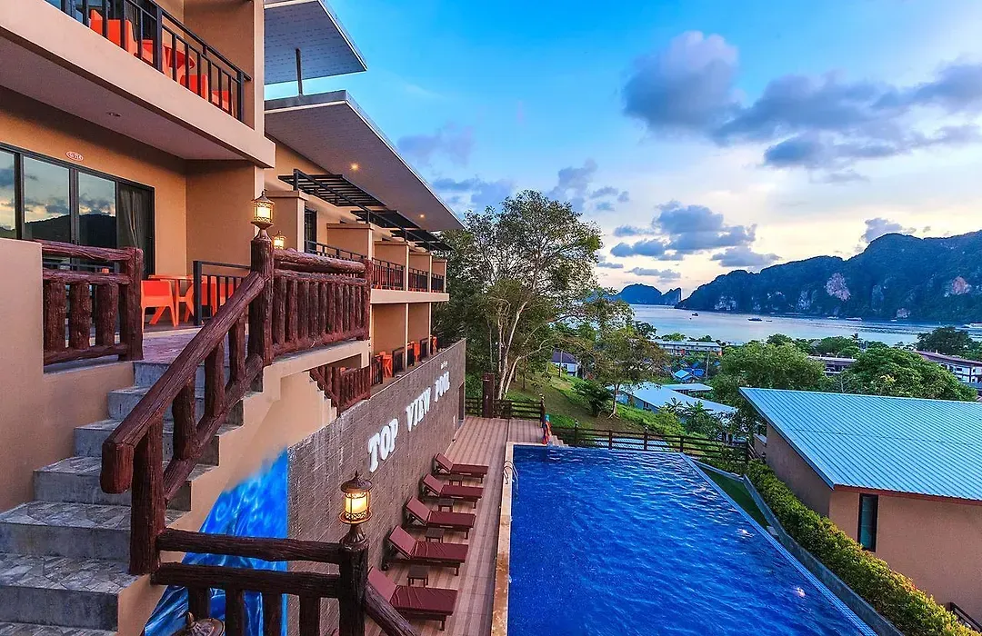 Infinity pool with sun loungers overlooking the sea and limestone cliffs at sunset